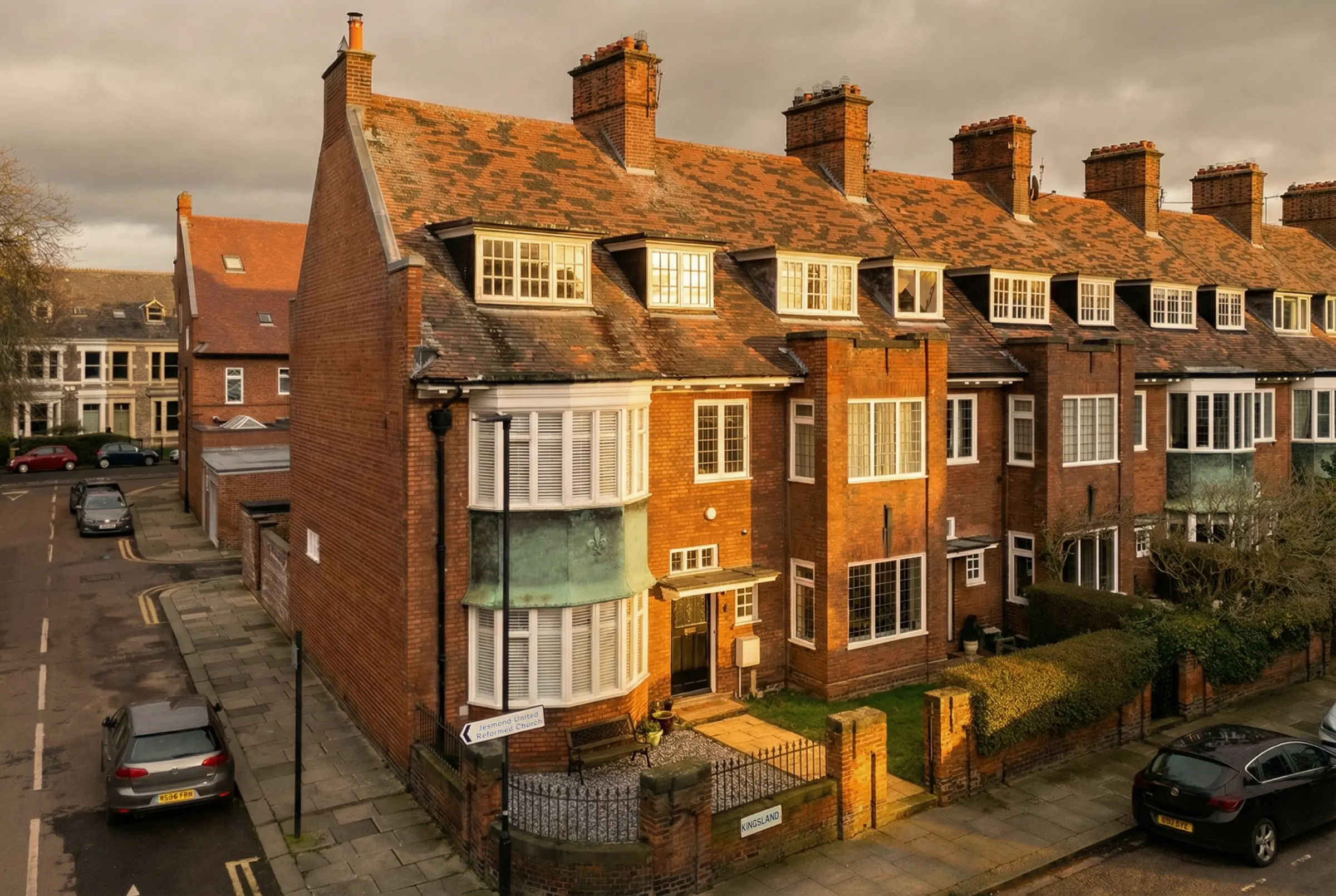 Modern red brick residential property with deep architectural shadows and warm golden hour reflections on windows.