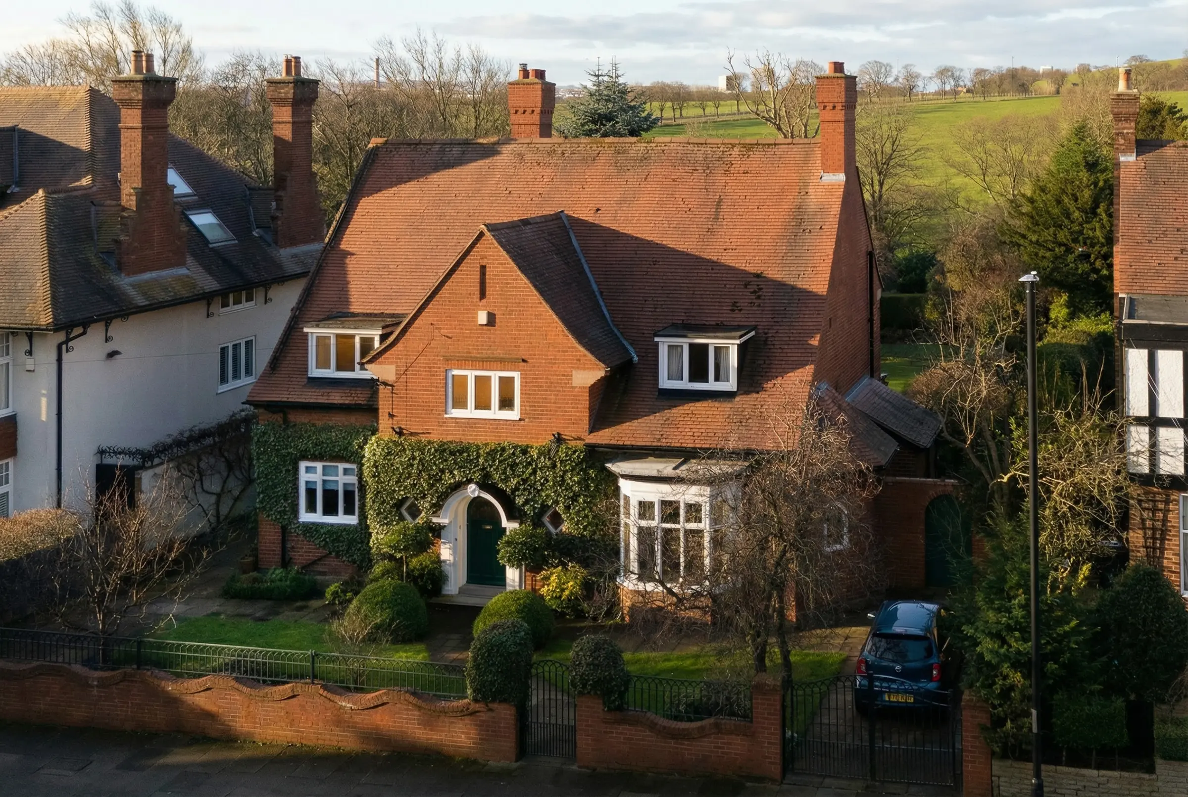 Estate residential property surrounded by vibrant landscaping and cool evening shadows.